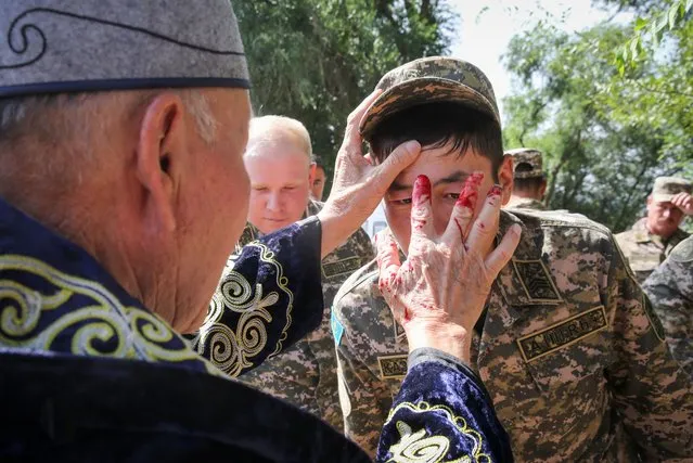 A muslim cleric puts a blood mark on the forehead of an army serviceman during celebrations of the Muslim festival of sacrifice Eid al-Adha, also known as Kurban Ait, in the village of Uzynagash outside Almaty, Kazakhstan on July 20, 2021. (Photo by Pavel Mikheyev/Reuters)