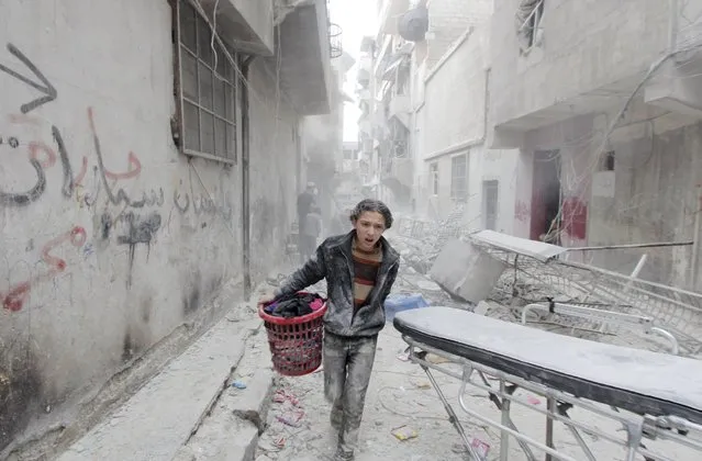 A boy carries his belongings at a site hit by what activists said was a barrel bomb dropped by forces loyal to Syria's President Bashar al-Assad in Aleppo's al-Fardous district April 2, 2015. (Photo by Rami Zayat/Reuters)