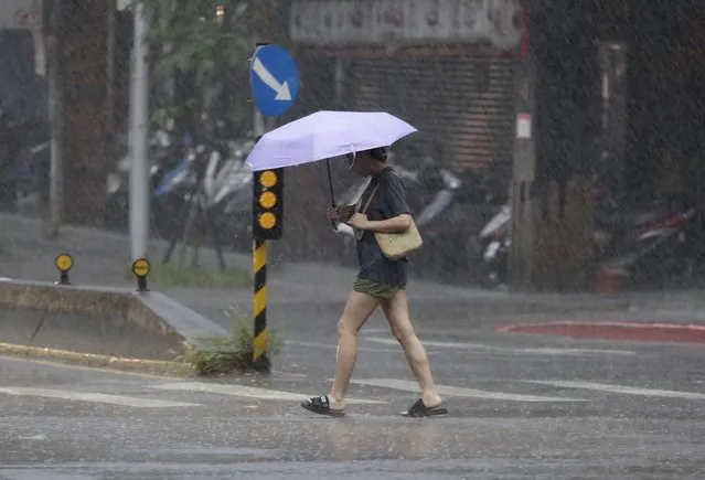 A woman walks in the rain as Typhoon Koinu approaches to Taiwan in Taipei, Taiwan, Wednesday, October 4, 2023. (Photo by Chiang Ying-ying/AP Photo)