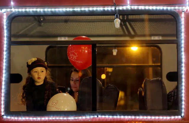 A girl looks through a window of the tourist train “La Sabana” decorated with Christmas lights in Bogota, Colombia on December 11, 2018. (Photo by Luisa Gonzalez/Reuters)