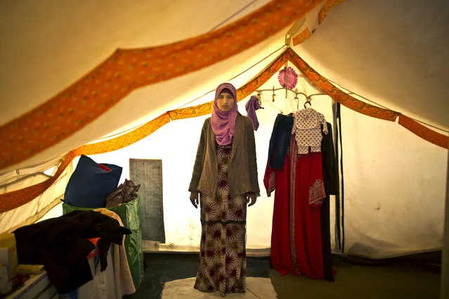 In this Monday, March 16, 2015 photo, Syrian refugee Khalida Alfarraj, 22, who is pregnant with her first child, poses for a portrait inside her tent at an informal tented settlement near the Syrian border, on the outskirts of Mafraq, Jordan. She suffers from low blood sugar and dizziness two months into her pregnancy, but cannot afford medicine. “I want to send a message to every pregnant woman in the world, feel blessed to have a safe roof and a family around you”, she said. (Photo by Muhammed Muheisen/AP Photo)