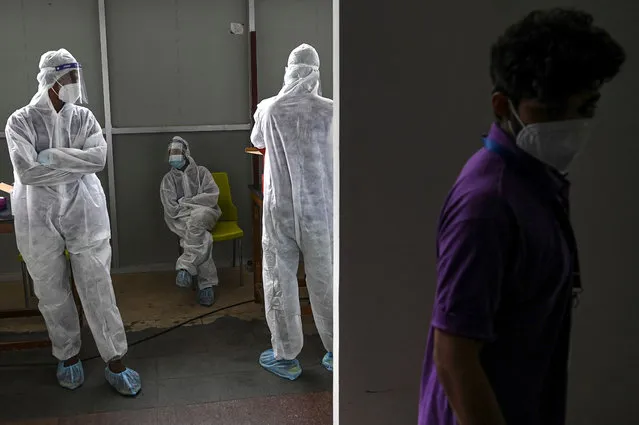 Health worker wait to collect samples form passengers arriving on international flights to test for the Covid-19 coronavirus at Anna International Airport in Chennai on August 1, 2021. (Photo by Arun Sankar/AFP Photo)