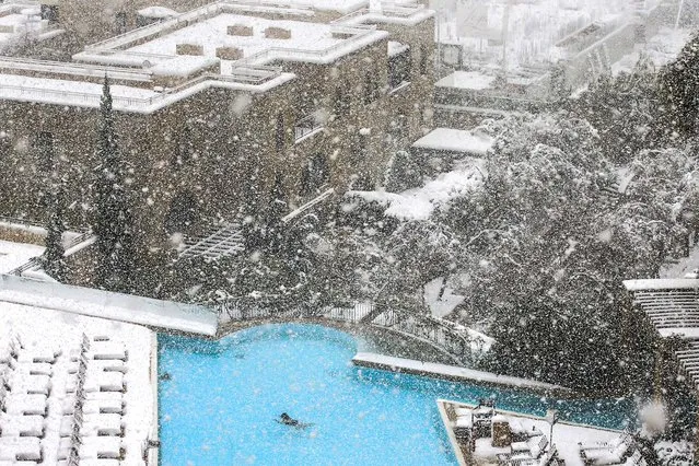 A woman swims in the pool at the David Citadel Hotel as it snows in Jerusalem, on December 13, 2013. A snowstorm of rare intensity blanketed the Jerusalem area and parts of the occupied West Bank on Friday, choking off the city and stranding hundreds in vehicles on impassable roads. (Photo by Brian Snyder/Pool)