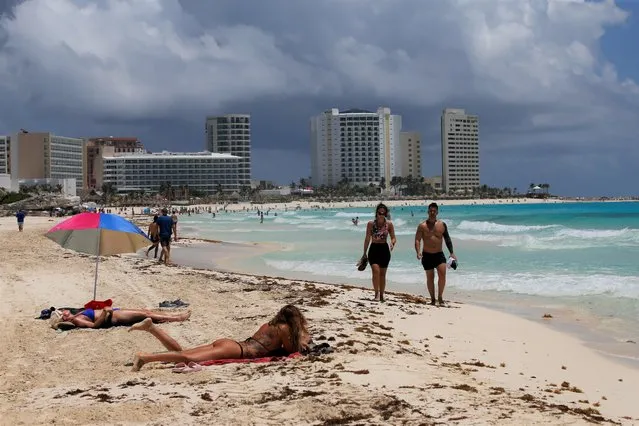 Tourists sunbathe on the beach before the arrival of Hurricane Grace, in Cancun, Quintana Roo State, Mexico, Wednesday, August 18, 2021. Residents and tourists along the Caribbean coast began making preparations for Grace, a storm that drenched Haiti and Jamaica and is now forecast to hit the gems of Mexico's tourism industry like a hurricane early Thursday morning. (Photo by Marco Ugarte/AP Photo)