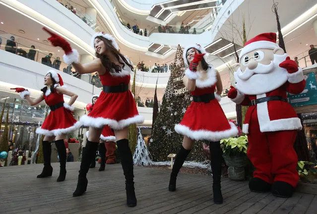 Employees dressed as Santa Claus perform as part of a shopping mall's Christmas celebrations in Seoul, South Korea, Tuesday, December 24, 2013. (Photo by Ahn Young-joon/AP Photo)