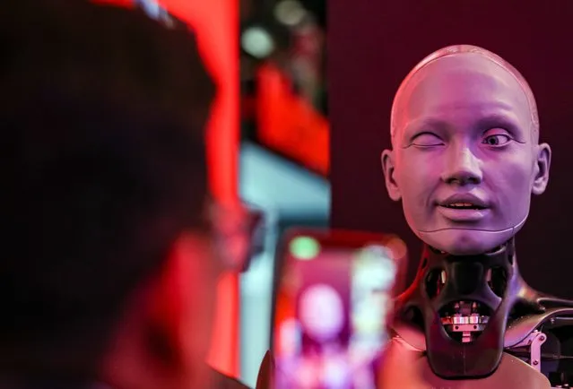 The world's most advanced humanoid shaped robot “Ameca” (R) gives a wink to visitor at Etisalat section at the Gulf Information Technology Exhibition (GITEX) Global 2022 in the Gulf emirate of Dubai, United Arab Emirates, 13 October 2022. The 42nd edition of the annual GITEX Global runs till 14 October 2022 and showcases around 5000 of IT companies from 90 countries. (Photo by Ali Haider/EPA/EFE)