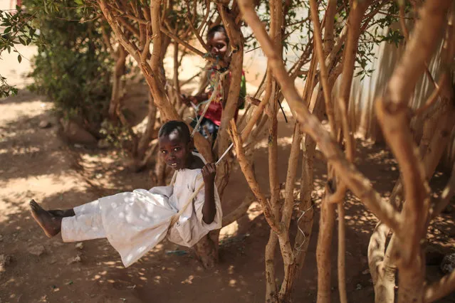 In this picture taken on Tuesday, April 14, 2015, Sudanese boys play on a makeshift swing outside their school in Izba, an impoverished neighborhood on the outskirts of Khartoum, Sudan. Izba is one of Khartoum's densely populated districts only 12 kilometers from the center of the Sudanese capital. (Photo by Mosa'ab Elshamy/AP Photo)