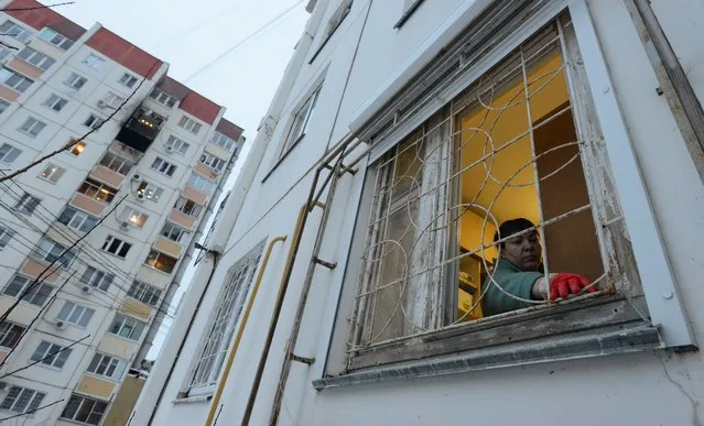 A woman removes broken glass next to a damaged multi-storey apartment block following a reported drone attack in Voronezh, Russia on January 16, 2024. (Photo by Reuters/Stringer)
