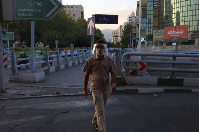 A man wearing protective face mask and shield to help prevent the spread of the coronavirus crosses a street in central Tehran, Iran, Sunday, August 8, 2021. (Photo by Vahid Salemi/AP Photo)