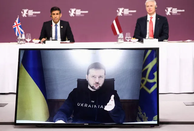 Ukrainian President Volodymyr Zelensky is displayed on a screen as he speaks via video link as Latvian Prime Minister Krisjanis Karins (R) and British Prime Minister Rishi Sunak listen during a Joint Expeditionary Force (JEF) plenary session in Riga, Latvia December 19, 2022. (Photo by Henry Nicholls/Pool via AFP Photo)