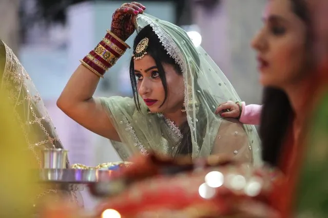 An Indian Hindu married woman offers prayers during Karva Chauth festival in Jammu, India, Sunday, October 24, 2021. Hindu married women decorate their hands with henna, wear colorful bangles and observe a fast to pray for the longevity and well being of their husbands during this festival. (Photo by Channi Anand/AP Photo)