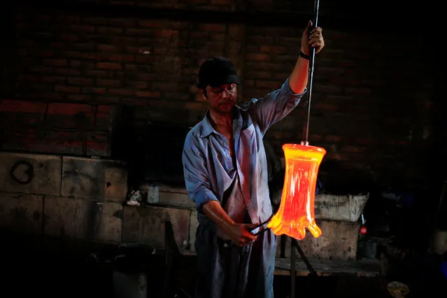 A glassmaker forms molten glass next to a furnace at Cespedes factory in Olocuilta, El Salvador February 8, 2017. (Photo by Jose Cabezas/Reuters)