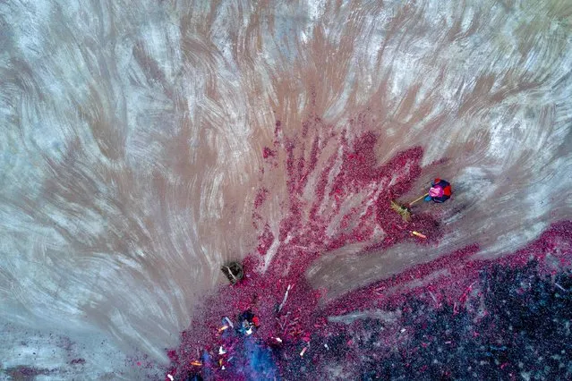 This aerial picture taken on February 10, 2017 shows a woman cleaning the village square after firecracker were set off as part of the “beat the Buddha” celebration in Yuxi village. Villagers in China's eastern Fujian province have a unique way of worshipping Buddha: they beat a rock statue of the diety to wish for a good new year and an abundant harvest. The religious ceremony held Friday in Yuxi village is one of many in the run-up to the traditional Lantern Festival, which falls on February 11 this year. (Photo by Johannes Eisele/AFP Photo)