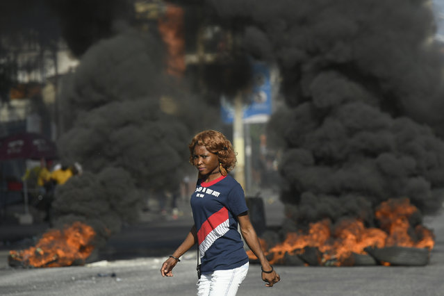 A pedestrian passes a burning roadblock set by anti-government protesters in Port-au-Prince, Haiti, Thursday, October 28, 2021. Haiti is struggling with a spike in gang-related kidnappings after President Jovenel Moïse was fatally shot at his private residence on July 7, a magnitude 7.2 earthquake killed more than 2,200 people in August and severe fuel shortages. (Photo by Matias Delacroix/AP Photo)