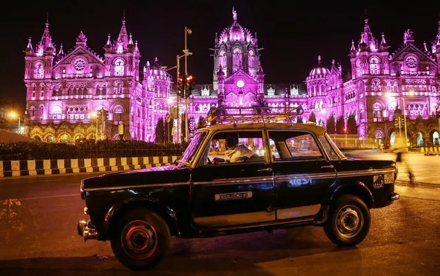 A taxi in front of the Chhatrapati Shivaji Terminus railway station, that's lit up in pink in support of International Women's Day, in Mumbai, India, 08 February 2016. (Photo by Divyakant Solanki/EPA)