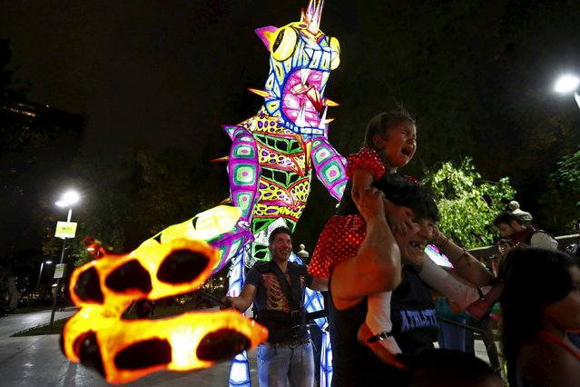 A girl cries as an Alebrije, a folk art sculpture of mythical creatures, follows during the International Festival of Lights in downtown Mexico City May 7, 2015. (Photo by Edgard Garrido/Reuters)