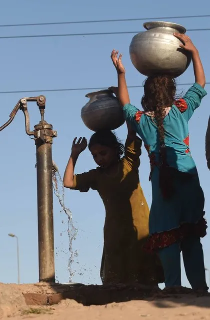 Pakistani girls fill water pots from a hand pump at a slum area of Lahore on March 21, 2016, on the eve of World Water Day. International World Water Day is held annually on March 22 to focus global attention on the importance of water and advocating for the sustainable management of our water resources. (Photo by Arif Ali/AFP Photo)