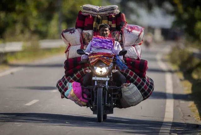 A vendor carries mattresses and cushions for sale on a motorbike in Gauhati, India, Tuesday, November 9, 2021. (Photo by Anupam Nath/AP Photo)