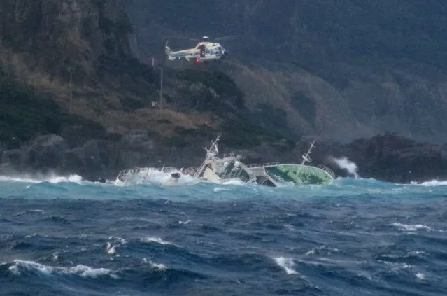 This handout photo taken on March 4, 2024 and released by Japan's 3rd Regional Coast Guard Headquarters shows a helicopter conducting a rescue operation after a ship lost power and drifted ashore on Kozushima Island, south of Tokyo. One person was missing and 24 others were rescued on March 4 after their fishing boat lost power and drifted onto rocks in rough seas off Japan, the coast guard said. (Photo by Japan's 3rd Regional Coast Guard Headquarters/Handout via AFP Photo)