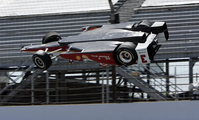 The car driven by Helio Castroneves, of Brazil, is airborne after hitting the wall in the first turn during practice for the Indianapolis 500 auto race at Indianapolis Motor Speedway in Indianapolis, Wednesday, May 13, 2015. (Photo by Joe Watts/AP Photo)