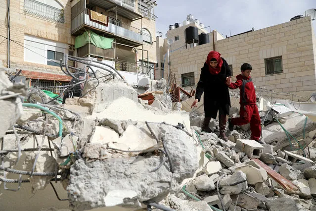 A Palestinian woman and her son walk on rubble from their house which was demolished by Jerusalem municipality workers as they did not a building permit, in the East Jerusalem neighbourhood of Beit Hanina February 22, 2017. (Photo by Ammar Awad/Reuters)