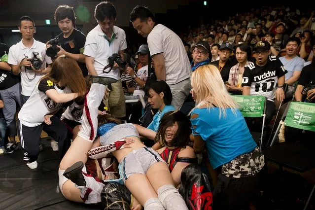 Members of the audience watch female wrestlers fight outside of the ring during a Stardom female professional wrestling show at Korakuen Hall in Tokyo, Japan, July 26, 2015. (Photo by Thomas Peter/Reuters)