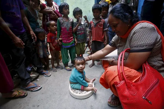 A health worker (R) weighs a child under a government program in New Delhi, India, May 7, 2015. (Photo by Anindito Mukherjee/Reuters)