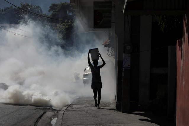 A woman walks amid tear gas fired by police during a protest against insecurity and water shortages, in Port-au-Prince, Haiti, November 18, 2021. (Photo by Ralph Tedy Erol/Reuters)