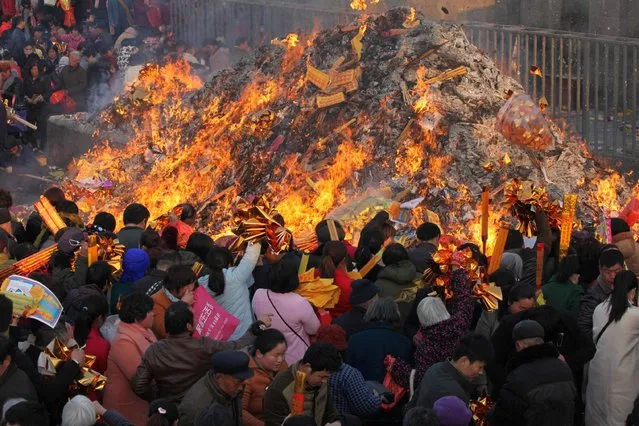 This photo taken on February 27, 2017 shows pilgrims throwing items into a bonfire during a temple fair at the Tai Hao Tomb Temple in Huaiyang County in Zhoukou in China's central Henan province. Visitors and pilgrims from home and abroad gathered at the temple to pay homage to Tai Hao, one of the ancestors of the nation according to Chinese mythology. (Photo by AFP Photo/Stringer)