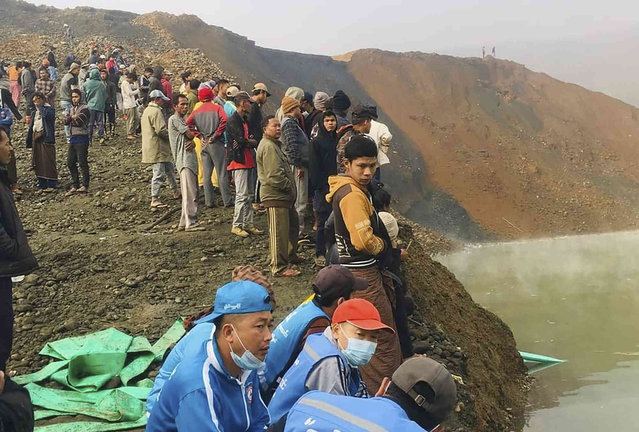People stand while members of rescue team search for missing people at a jade mining area Wednesday, December 22, 2021, in Hpakant, Kachin State, northern Myanmar. (Photo by AP Photo/Stringer)