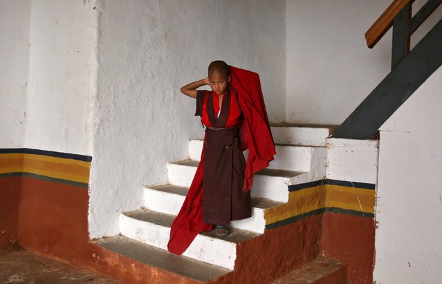 A young monk fixes his robe inside the Punakha Dzong, Bhutan, April 17, 2016. (Photo by Cathal McNaughton/Reuters)