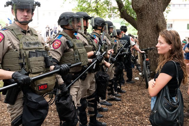A student quietly stares at a row of Texas State Troopers as pro-Palestinian students protest the Israel-Hamas war on the campus of the University of Texas in Austin, Texas, on April 24, 2024. Universities have become the focus of intense cultural debate in the United States since the October 7 Hamas attack and Israel's overwhelming military response to it. (Photo by Suzanne Cordeiro/AFP Photo)