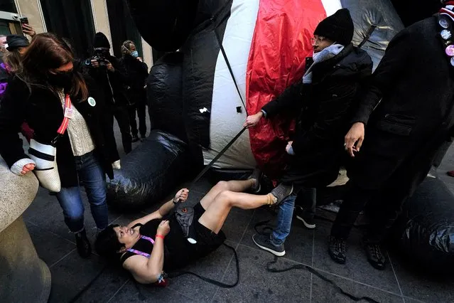 Patricia Cabuay lays on the ground in front of a “Trump Rat” inflatable effigy during an altercation with anti Donald Trump protesters at Fox News Headquarters in the Manhattan borough of New York City, New York, U.S., January 6, 2022. (Photo by Carlo Allegri/Reuters)