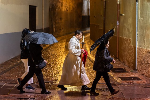 A penitent from the “Real Hermandad del Santisimo Cristo de las Injurias, Cofradia del Silencio” brotherhood walks along the street after his procession was suspended due to the rain, during Holy Week in the northwestern Spanish city of Zamora on March 27, 2024. Christian believers around the world mark the Holy Week of Easter in celebration of the crucifixion and resurrection of Jesus Christ. (Photo by Cesar Manso/AFP Photo)