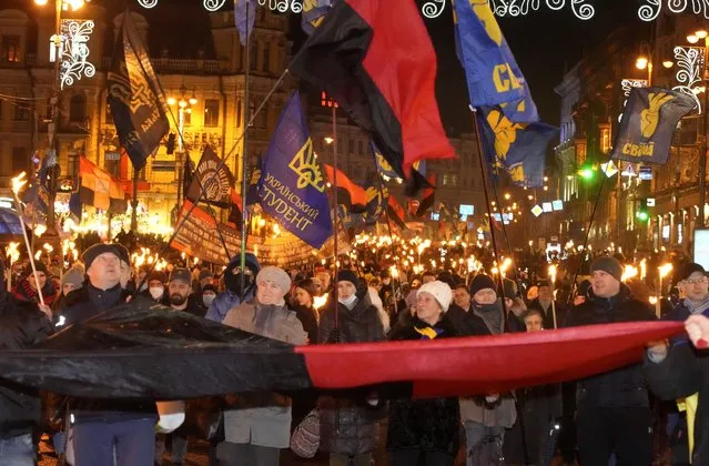 Activists of various nationalist parties carry torches during a rally in Kyiv, Ukraine, Saturday, January 1, 2022. The rally was organized to mark the birth anniversary of Stepan Bandera, founder of a rebel army that fought against the Soviet regime and who was assassinated in Germany in 1959. (Photo by Efrem Lukatsky/AP Photo)