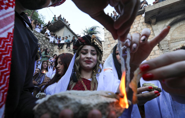 Iraqi Yazidis light candles outside the Temple of Lalish in a valley near the Kurdish city of Dohuk on April 16, 2024, during a ceremony marking the Yazidi New Year. The Yazidis, who number about 1.6 million, commemorate the arrival of light into the world during the new year celebrations. (Photo by Safin Hamid/AFP Photo)
