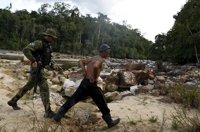 An agent of Brazil’s environmental agency detains a man at an illegal gold mine during an operation against illegal gold mining on indigenous land, in the heart of the Amazon rainforest, in Roraima state, Brazil April 18, 2016. (Photo by Bruno Kelly/Reuters)