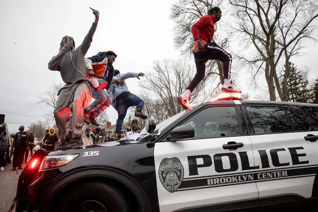 Men jump on police vehicles near the site of a shooting involving a police officer, Sunday, April 11, 2021, in Brooklyn Center, Minn. (Photo by Carlos Gonzalez/Star Tribune via AP Photo)