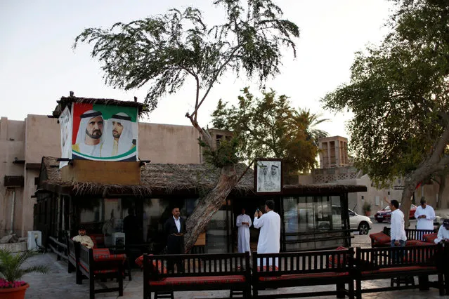 A picture of Sheikh Mohammed bin Rashid Al Maktoum (L), Prime Minister and Vice President of the United Arab Emirates and Ruler of Dubai, is seen as visitors stand at a coffee shop in Al Bastakiya, a historic district in Dubai, UAE March 10, 2016. (Photo by Ahmed Jadallah/Reuters)