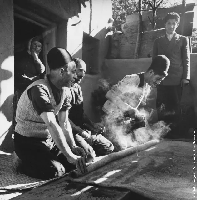 1950:  Iranian peasants making rugs by kneading pieces of wool together after steaming them under pressure