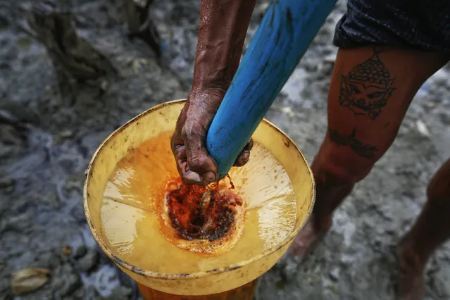 Ko Min, 26, manually extracts oil from one of three 300 feet deep wells he works on in the Minhla township of the Magwe district October 27, 2013. Everyday, Ko Min makes around $30 extracting crude oil from three small wells after he bought rights to use them for close to $1000 from a farmer who owns the land. (Photo by Damir Sagolj/Reuters)