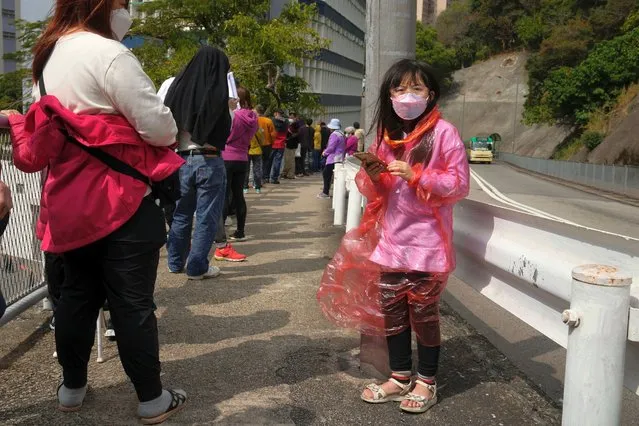 Residents line up to get tested for the coronavirus at a temporary testing center for COVID-19, in Hong Kong, Tuesday, February 15, 2022. Hong Kong's leader on Tuesday said a surge of coronavirus cases is overwhelming the city's emergency resources, but defended strict measures that have been imposed. (Photo by Kin Cheung/AP Photo)