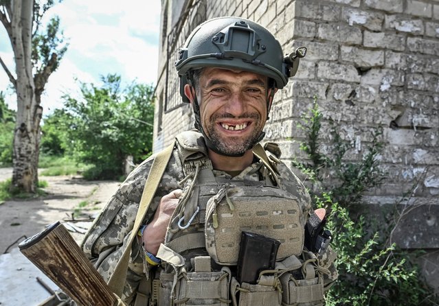 A Ukrainian serviceman smiles on May 21, 2024 during a moment of calm in the southeastern town of Orikhiv, Zaporizhzhia, which has been heavily damaged by Russian military strikes. (Photo by Reuters/Stringer)