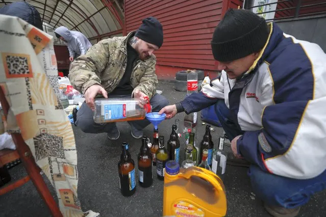 Ukrainians prepare Molotov cocktails outside their home in Kiev (Kyiv), Ukraine, 01 March 2022. (Photo by Sergey Dolzhenko/EPA/EFE)