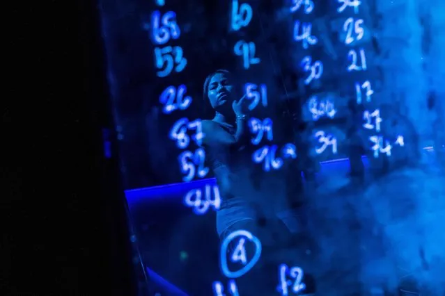 This photo taken on March 29, 2017 shows a pole dancer' s reflection on a board with numbers assigned to dancers at a go- go bar in Walking Street, a renowned red light district in Pattaya. (Photo by Roberto Schmidt/AFP Photo)