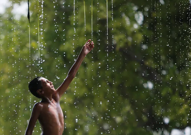 A boy cools off under a water fountain on a hot summer day in New Delhi, India, May 12, 2016. (Photo by Anindito Mukherjee/Reuters)