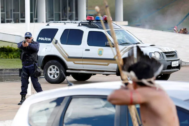Riot police points his gun at Brazilian Indians during a demonstration against the violation of indigenous people's rights, in Brasilia, Brazil April 25, 2017. (Photo by Gregg Newton/Reuters)