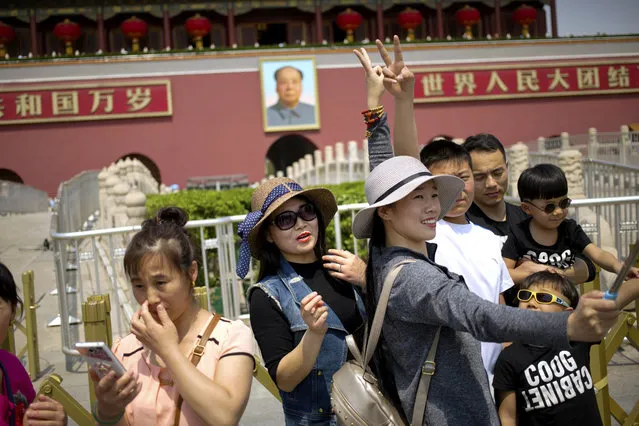 Women gesture as they pose for a selfie in front of Tiananmen Gate during the May Day holiday in Beijing, Monday, May 1, 2017. Millions of Chinese are taking advantage of the May Day holidays to visit popular tourist sites. (Photo by Mark Schiefelbein/AP Photo)