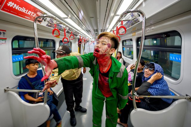 Passengers watch a performer acting as a zombie on a train coach during the “Train to Apocalypse” event as part of the Pandora Box Artmire Festival 2024 held to attract commuters to ride the city's rapid transit system LRT (light rapid transit), in Jakarta on July 11, 2024. (Photo by Bay Ismoyo/AFP Photo)