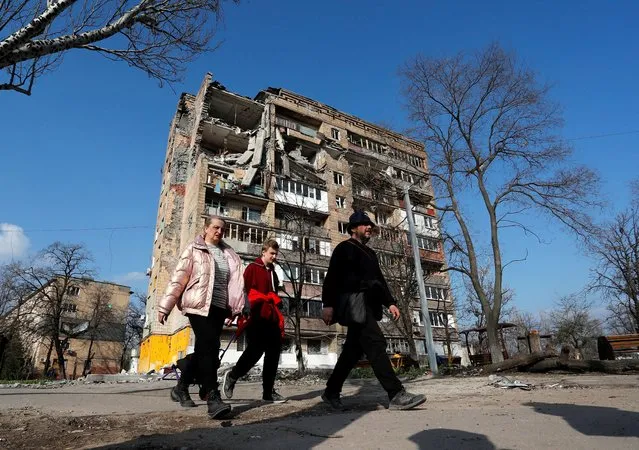 Local residents walk past an apartment building damaged during Ukraine-Russia conflict in the southern port city of Mariupol, Ukraine on April 15, 2022. (Photo by Alexander Ermochenko/Reuters)